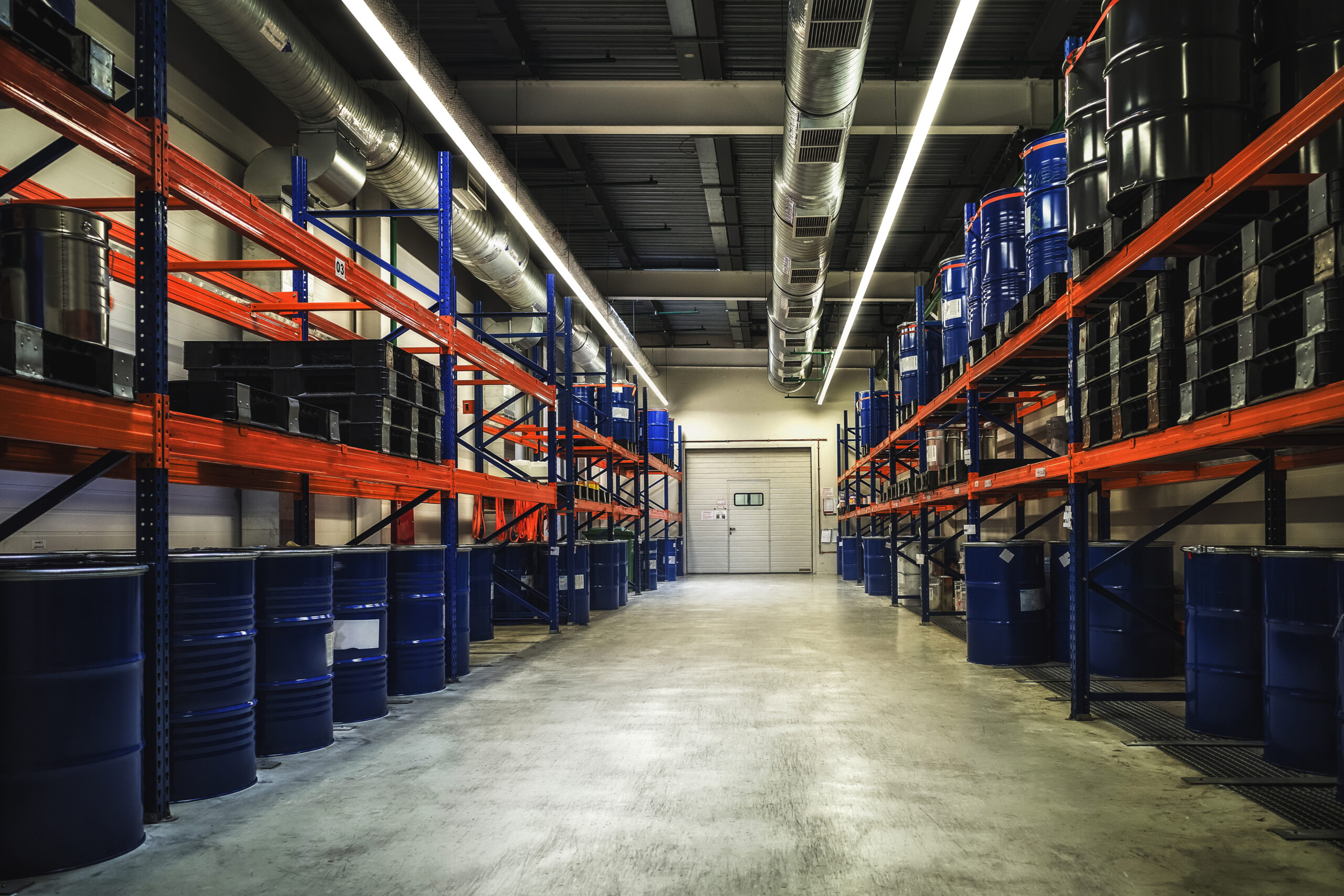 Blue metal barrels. Chemical industry. Metal barrels for chemicals. Storage racks. Barrels are stored in a warehouse. Warehouse storage.